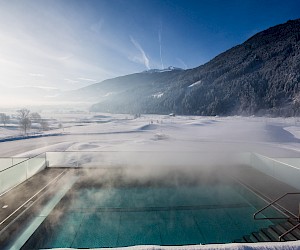 Das beheizte Infinity Pool der Sportresidenz Zillertal mit Ausblick auf die Zillertaler Berge und den Golfplatz.